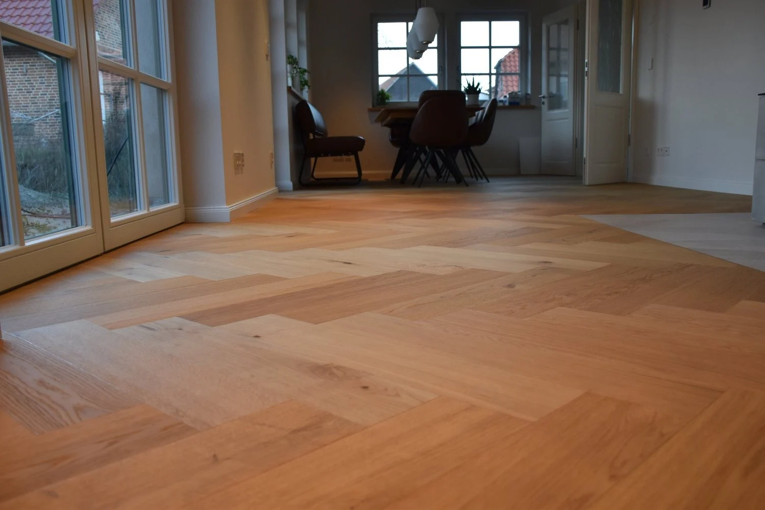 Verlegter Holzfußboden im Wohnraum mit bodentiefen Fenstern