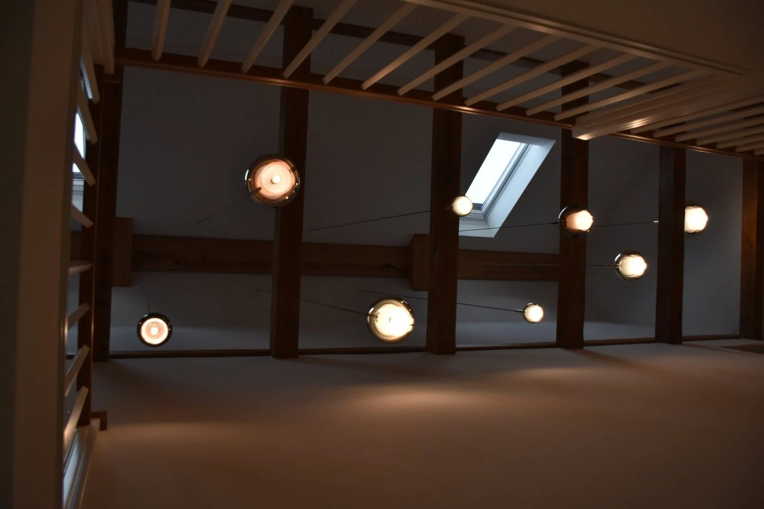 Offener Innenraum mit sichtbaren Holzstreben, Balkendecke und Pendelleuchten
