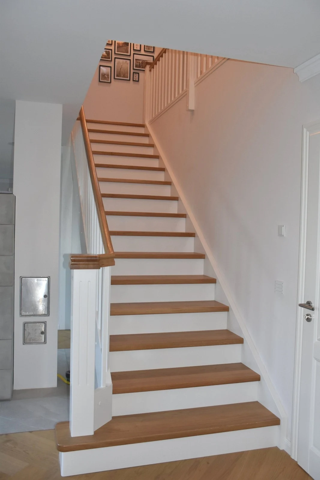 Geradläufige Treppe mit Holzstufen und weißen Wangen und Geländerstäben